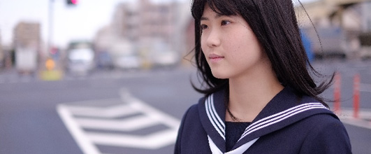 素材サイト写真AC より、交差点を渡る女子高生。 アイキャッチ画像。