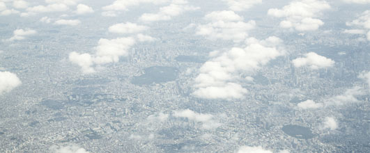 写真素材サイト「PAKUTASO」より、「雲の上から東京の様子」。 アイキャッチ画像。