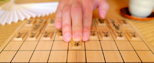 素材サイト「写真AC」より、「将棋の駒を進める男性の手」。毛並良好さんの作品。 アイキャッチ画像。